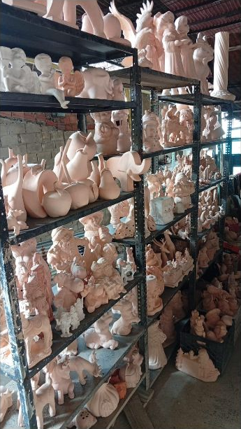 Estantes del taller Cerámicas Gabriel con jarrones, figuras y piezas decorativas sin pintar